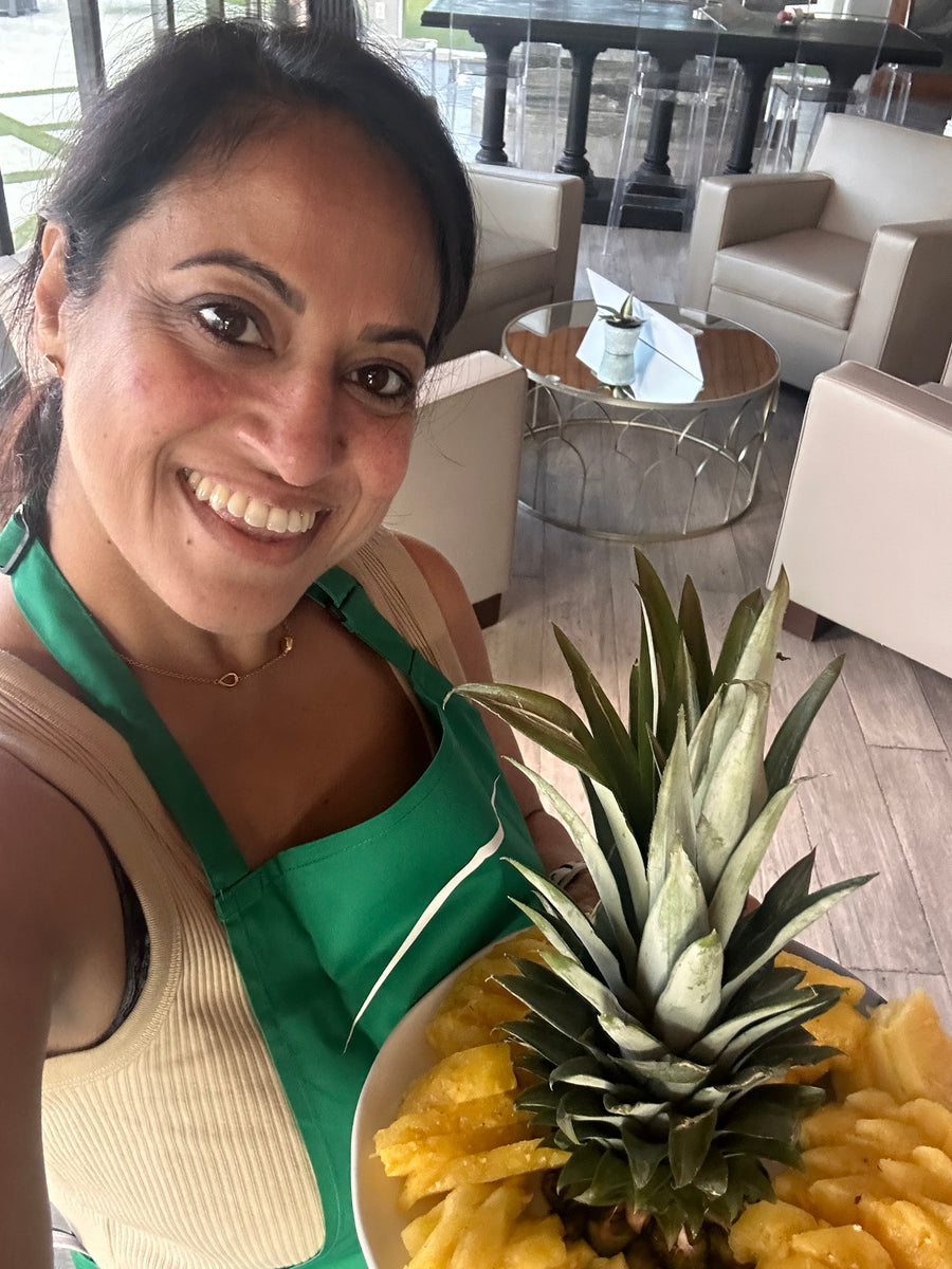 Nourish & Bloom chef smiling in the kitchen holding a fresh pineapple